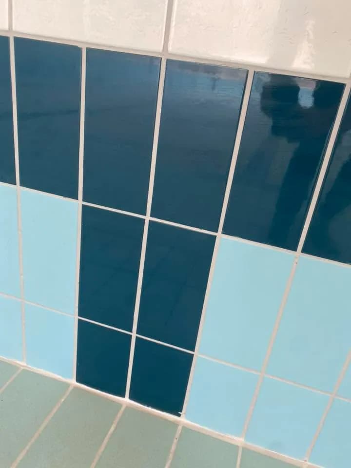 תקריב של פוגות בהירות בין אריחים כחולים בדופן וברצפת בריכה
